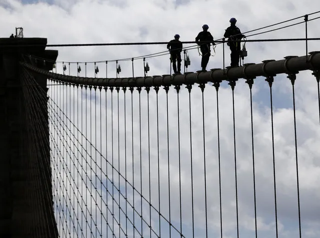 In this Tuesday, May 2, 2017 photo, New York City police officers, including members of the Emergency Services Unit, walk down a cable on the Brooklyn Bridge during a training exercise in New York. The 400-team unit, an elite group of officers trained to handle the city’s most dangerous rescues, trains for months not only on technical rescue techniques, but also on how to talk to people to get them down safely. (Photo by Seth Wenig/AP Photo)