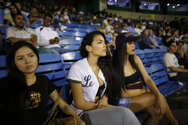 Fans of the Leones de Caracas team watch the opening winter season game between their team and Tigres de Aragua in Caracas, Venezuela, Tuesday, November 5, 2019. The luxury of a night of fun for a couple buying tickets, beer and hotdogs easily cost double the monthly minimum wage equal to the $15 that most Venezuelans earn. (Photo by Ariana Cubillos/AP Photo)