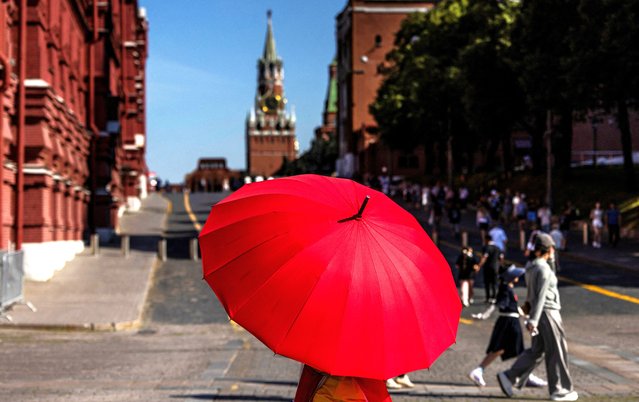 A person with red umbrella walks near Red Square during hot weather in Moscow, Russia on July 17, 2024. (Photo by Maxim Shemetov/Reuters)