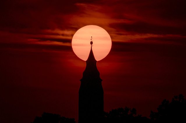 The tower of the reformed church is silhouetted by the setting Sun near Tiszafoldvar, Hungary, 25 July 2024. (Photo by Peter Komka/EPA/EFE)