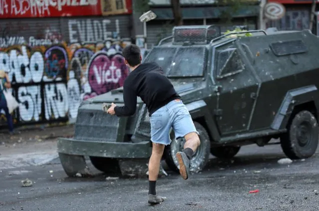 A demonstrator throws a rock at a police vehicle during a protest against Chile's government in Santiago, Chile on December 18, 2019. (Photo by Andres Martinez Casares/Reuters)