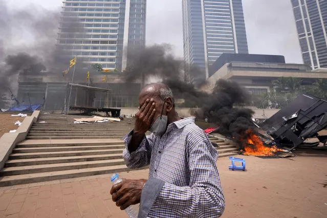 A Sri Lankan man reacts to tear gas as he walks past the vandalized site of anti-government protests outside president's office in Colombo, Sri Lanka, Monday, May 9, 2022. (Photo by Eranga Jayawardena/AP Photo)