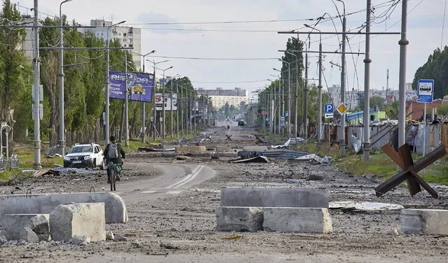 A man rides a bicycle on a damaged street on the outskirts of Kharkiv, Ukraine, 14 May 2022. Kharkiv, Ukraine's second-largest city, has witnessed repeated airstrikes and had only recently been freed from Russian troops by the Ukrainian army. On 24 February, Russian troops had invaded Ukrainian territory starting a conflict that has provoked destruction and a humanitarian crisis since. According to the UNHCR report on the situation of Ukraine released on 11 May, more than six million refugees have fled Ukraine and further 7.7 million people have been displaced internally, making this the fastest growing refugee crisis since World War II. (Photo by Sergey Kozlov/EPA/EFE)