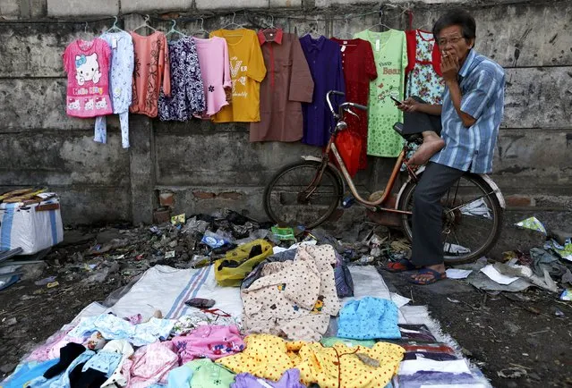 A man selling clothes smokes a cigarette while waiting costumers near Duri train station in Jakarta, Indonesia August 3, 2015. Indonesia's economic growth is expected to have slowed in the second quarter to the weakest level in nearly six years, despite the government's promise to jumpstart the economy after a dismal first quarter. (Photo by Reuters/Beawiharta)