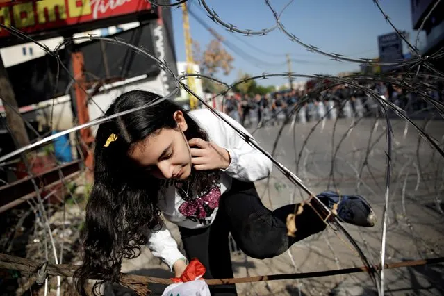A girl walks among a barbed wire blocking the road to the U.S. Embassy during a protest in Awkar, Lebanon on November 24, 2019. (Photo by Andres Martinez Casares/Reuters)