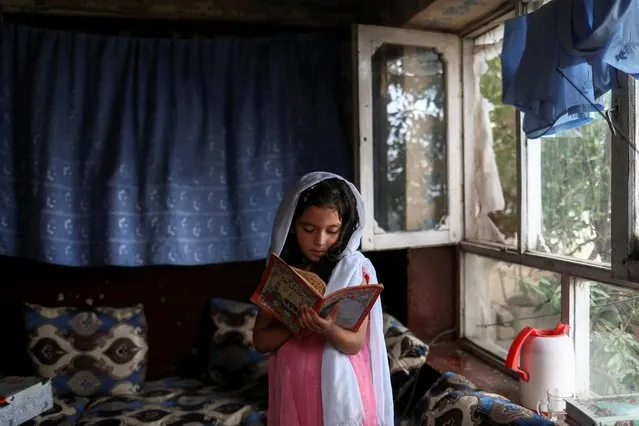 An Afghan girl reads a book inside her home in Kabul, Afghanistan, June 13, 2022. (Photo by Ali Khara/Reuters)
