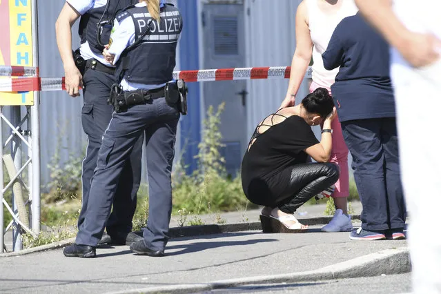 A visitor, center,  waits to be questioned by police near a discotheque in Constance, at Lake Constance, Germany, Sunday, July 30, 2017. Police say a shooting in Germany’s Baden-Wurttemberg state has claimed two lives, including that of the gunman. They say the early-morning shooting Sunday at a discotheque in the town of Constance also left three guests seriously wounded. A tweet by Constance police says one person was killed by the shooter when he opened fire, also wounding the other victims. He then fled, was shot by police and died later in hospital. (Photo by Felix Kaestle/DPA via AP Photo)