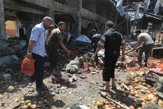 Men attempt to remove a dead body after what activists said were air strikes by forces loyal to Syria's President Bashar al-Assad on a marketplace in the Douma neighborhood of Damascus, Syria August 16, 2015. (Photo by Bassam Khabieh/Reuters)