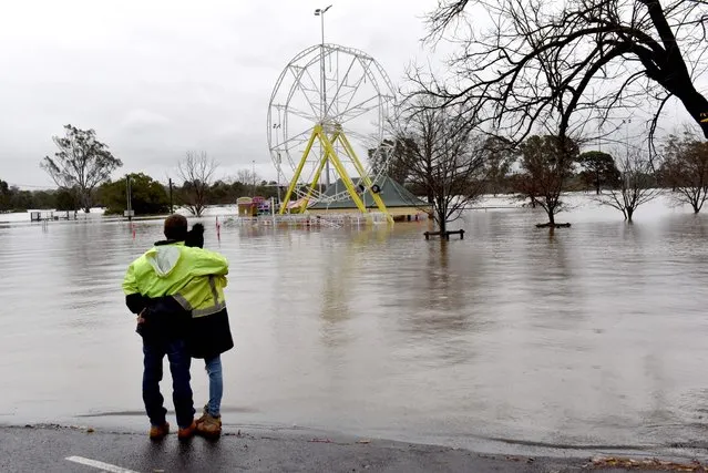 People look at a flooded park due to torrential rain in the Camden suburb of Sydney on July 3, 2022. Thousands of Australians were ordered to evacuate their homes in Sydney on July 3 as torrential rain battered the country's largest city and floodwaters inundated its outskirts. (Photo by Muhammad Farooq/AFP Photo)