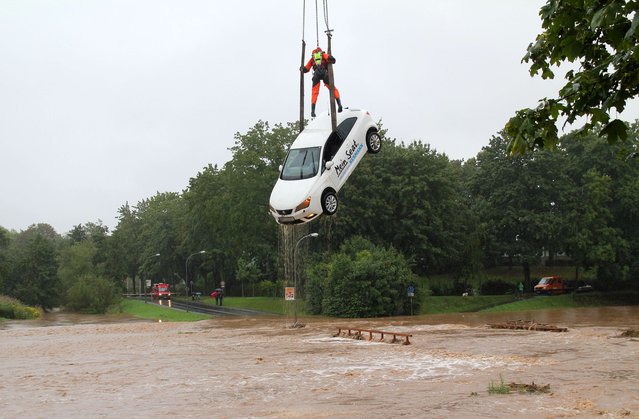 A fireworker stands on a car that is pulled out of over flooded areas of the river Leine in Goettingen, central Germany, on August 17, 2015. (Photo by Stefan Rampfel/AFP Photo/DPA)