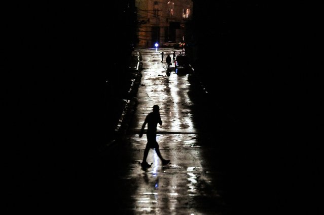 People walk on a darkened street due to a blackout after the pass of hurricane Rafael in Havana, on November 6, 2024. Hurricane Rafael left Cuba on Wednesday night, leaving the island in darkness with widespread power outages and destruction in some villages after hitting as a powerful Category 3 hurricane. (Photo by Yamil Lage/AFP Photo)