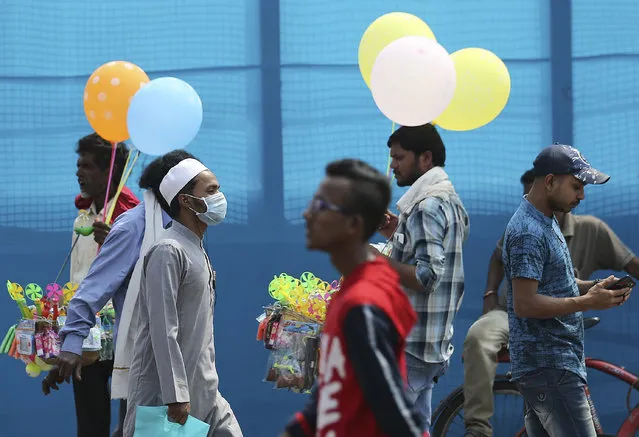 An Indian wears a mask and walks on a street in Hyderabad, India, Thursday, March 5, 2020. A new virus first detected in China has infected more than 90,000 people globally and caused over 3,100 deaths. The World Health Organization has named the illness COVID-19, referring to its origin late last year and the coronavirus that causes it. (Photo by Mahesh Kumar A./AP Photo)