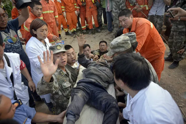 In this photo taken Tuesday, Aug. 5, 2014, earthquake survivor Xiong Zhengfen, 88, is evacuated by rescue workers after being buried under rubble for 50 hours in Ludian county in southwest China's Yunnan province. Some 10,000 troops and hundreds of volunteers have rushed to Ludian to clear roads and dig out possible survivors from the debris following Sunday's quake , but landslides and bouts of heavy rains have complicated rescue efforts. (Photo by AP Photo)