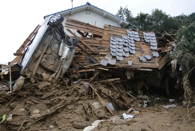 A dog takes a rest under a destroyed house at a site where a landslide swept through a residential area at Asaminami ward in Hiroshima, western Japan, August 20, 2014. At least 36 people, including several children, were killed in Japan on Wednesday, when landslides triggered by torrential rain slammed into the outskirts of the western city of Hiroshima, and the toll could rise further, police said. (Photo by Toru Hanai/Reuters)