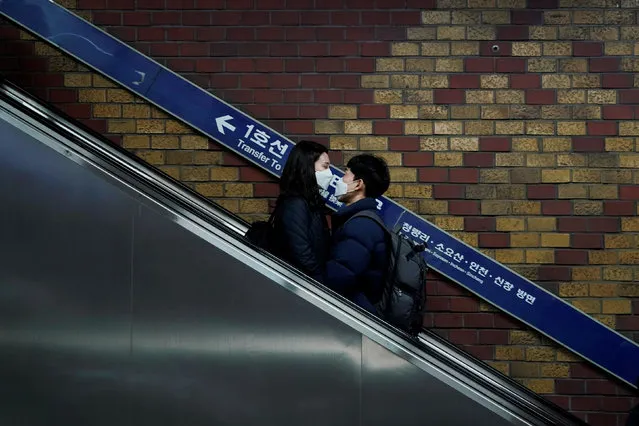 A couple wearing masks to prevent contacting the coronavirus rides on an escalator at a subway station in Seoul, South Korea, March 1, 2020. (Photo by Kim Hong-Ji/Reuters)