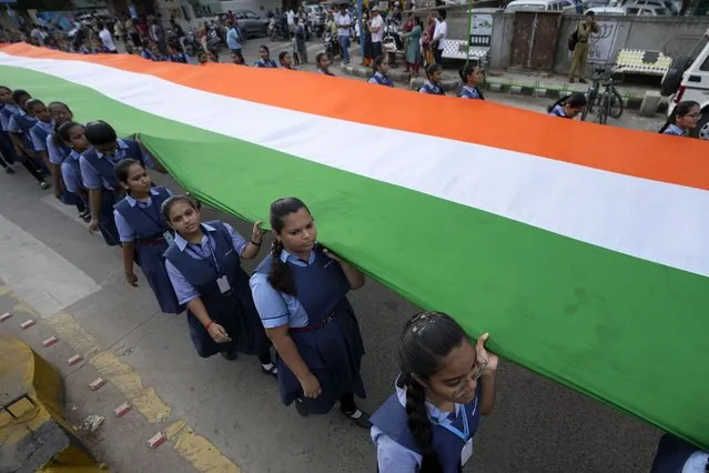 Students walk carrying a 1551 feet (473 meters) long Indian flag as they mark 75 years of India's Independence, in Ahmedabad, India, Monday, August 8, 2022. India is marking the 75th anniversary of its Independence from British colonial rule on Aug. 15. (Photo by Ajit Solanki/AP Photo)