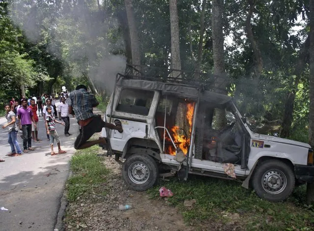 A demonstrator kicks a vehicle that was set on fire during a protest at Golaghat district in the northeastern Indian state of Assam August 20, 2014. Thousands of protesters in the far-flung Indian state of Assam defied a curfew and attacked police in a fifth day of unrest over a territorial dispute with a neighbouring state. (Photo by Reuters/Stringer)