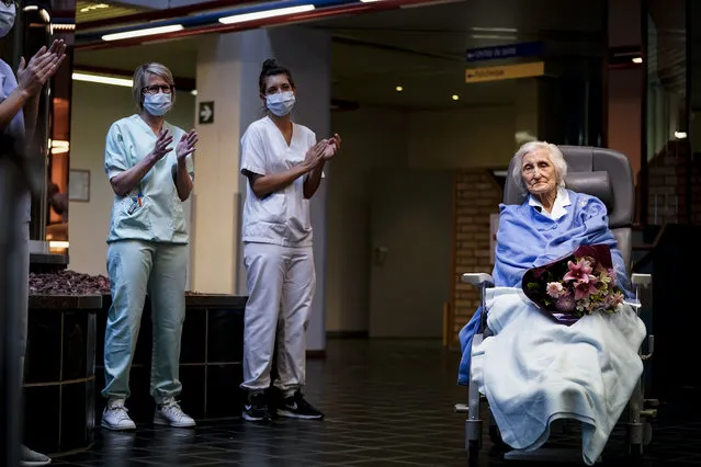 Medical workers clap as Belgian 100 year-old patient Julia Dewilde leaves the Bois de l'Abbaye hospital (CHBA) in Seraing, Belgium after being succesfully treated for COVID-19, the disease caused by the novel coronavirus, on April 29, 2020. (Photo by Kenzo Tribouillard/AFP Photo)