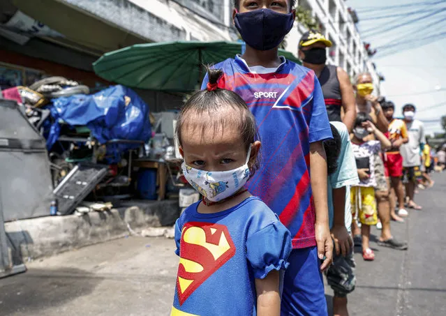 Thai poor children line up for free food distribution during the ongoing spread of COVID-19 coronavirus pandemic, at a slum community in Bangkok, Thailand, 22 April 2020. People are encouraged to stay home and maintain social distancing in an attempt to curb the spread of COVID-19 coronavirus pandemic. (Photo by Rungroj Yongrit/EPA/EFE/Rex Features/Shutterstock)