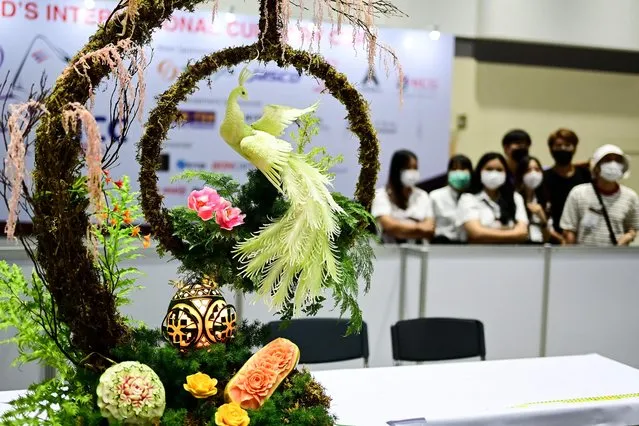 Visitors look at a carved fruits and vegetables decoration by Vietnamese participant Pham Van Dong during a fruit and vegetable carving competition at the 26th Thailand International Culinary Cup in Bangkok on September 21, 2022. (Photo by Manan Vatsyayana/AFP Photo)