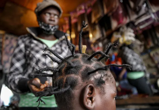 In this Sunday, May 3, 2020 file photo, Gettrueth Ambio, 12, has her hair styled in the shape of the new coronavirus, at the Mama Brayo Beauty Salon in the Kibera slum, or informal settlement, of Nairobi, Kenya. The coronavirus has revived a hairstyle in East Africa, one with braided spikes that echo the virus' distinctive shape, with the growing popularity in part due to economic hardships linked to virus restrictions. (Photo by Brian Inganga/AP Photo/File)
