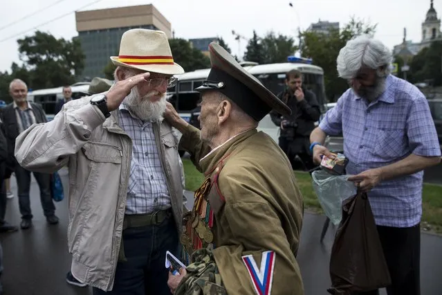 World War II veteran Lev Yatsevich, center, and Sergei Perminov, 65, left, both of whom turned up to oppose a hard-line Soviet coup in August 1991, greet each other during an event mark the 25th anniversary of the first day of the failed coup outside the Russian White House parliament building in Moscow, Russia, Friday, August 19, 2016. The defeat of the coup, which came several days later, setting in motion the dissolution of the Soviet Union, is widely regarded as a triumph of democracy in Russia. (Photo by Alexander Zemlianichenko/AP Photo)