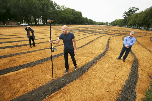 Cuban-American artist Jorge Rodriguez-Gerada demonstrates how a “rover”, or high-precision GPS marker, was used to create his six-acre sand and soil “facescape” on the JFK Hockey Field along the north side of the Reflecting Pool on the National Mall October 1, 2014 in Washington, DC. (Photo by Chip Somodevilla/Getty Images)