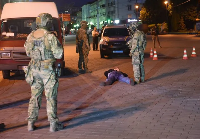A suspected hostage-taker lies on the ground after being detained by law enforcement officers in the city of Lutsk, some 400 kilometres (250 miles) from the capital Kiev, on July 21, 2020. The siege of a bus with 13 passengers by an armed man on Tuesday has ended with all the hostages freed, Ukrainian police said. (Photo by Yuriy Dyachyshyn/AFP Photo)