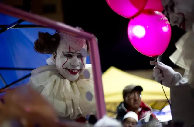A person dressed in a diabolical clown costume looks in the mirror at the start of the Zombie Walk in La Paz, Bolivia, late Saturday, October 28, 2017. The annual walk is a Halloween charity event to collect money to feed street animals, according to organizers. (Photo by Juan Karita/AP Photo)