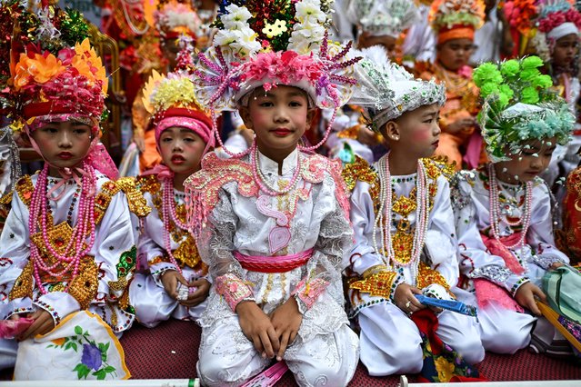 This photograph taken on March 28, 2025 shows young ethnic Shan boys wearing shimmering dresses and colourful floral headpieces ahead of taking part in the annual Poy Sang Long procession, a traditional rite of passage ceremony for young boys to be initiated as novice Buddhist monks at the Wat Ku Tao Buddhist temple in Chiang Mai in northern Thailand. Dressed in flowers, finery and makeup, scores of boys were paraded around a temple in Thailand before having their heads shaved – a symbolic start to a centuries-old Shan monkhood ordination. (Photo by Manan Vatsyayana/AFP Photo)