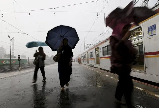 Women run to catch a train during a rainy day at a train station in Jakarta, Indonesia, May 4, 2015.  REUTERS/Beawiharta 