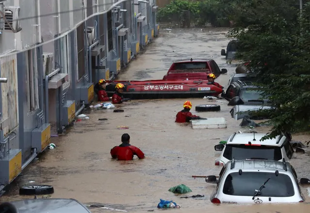 Rescue workers search near vehicles in a parking lot and lower sections of apartment buildings flooded due to heavy rain in Daejeon on July 30, 2020. (Photo by Yonhap/AFP Photo)