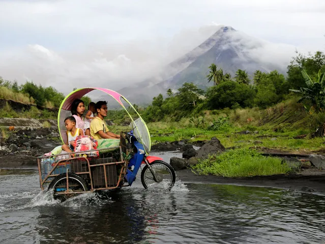 Filipino villagers with their belongings maneuver along the slopes of rumbling Mayon Volcano in Legaspi city, Albay province, Philippines 16 January 2018. The Philippines on 15 January raised the alert level due to the possibility of a hazardous eruption of the Mayon volcano, in the east of the country, after it spewed clouds of ashes over the weekend, leading to an evacuation of more than a thousand people. (Photo by Francis R. Malasig/EPA/EFE)