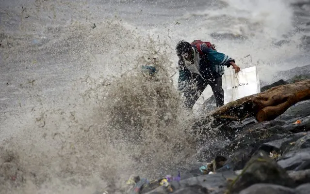 A resident looks for recyclable materials amidst strong waves due to Typhoon Koppu in Manila Bay, October 18, 2015. (Photo by Erik De Castro/Reuters)