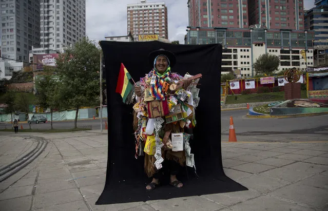 In this February 5, 2018 photo, Cornelio Colque Huanca, dressed as “Ekeko”, the god of prosperity and the central figure of the Alasita Fair, poses for a portrait in front of a black curtain in La Paz, Bolivia. Huanca, 56, said he's been selling plants at the annual Alasita fair over the last 39 years. “Everything I've asked him, he has given to me. That's why I always wanted to dress up as Ekeko”, said Huanca who took 5th place at the Ekeko competition. (Photo by Juan Karita/AP Photo)