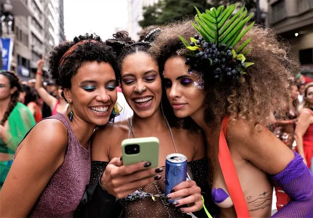 Revelers look at a cellphone during the annual street block party know as “Explode Coracao” on the third day of Carnival on February 19, 2023 in Sao Paulo, Brazil. According to the São Paulo City Council, during Carnival week more than 500 street blocks (blocos de rua) are held and more than 15 million people are expected to participate in them. Created in 2017, Explode Coracao is one of the most popular street blocks and attracted 150,000 revelers in its last edition, before the pandemic, in 2020. (Photo by Alexandre Schneider/Getty Images)