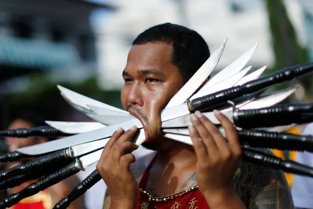 A devotee of the Chinese Samkong Shrine walks with knives pierced on his mouth during a procession celebrating the annual vegetarian festival in Phuket, Thailand October 4, 2016. (Photo by Jorge Silva/Reuters)