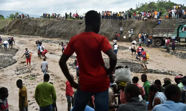 Haitian people cross the river La Digue in Petit Goave where the bridge collapsed during the rains of the Hurricane Matthew, southwest of Port-au-Prince, October 5, 2016. (Photo by Hector Retamal/AFP Photo)