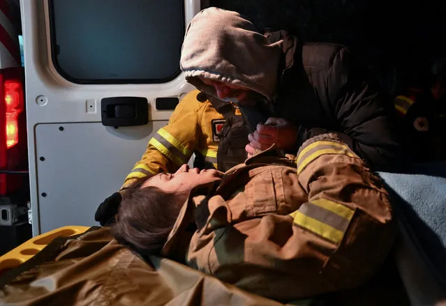 Local resident Yurii holds the hand of his pregnant relative Anna, 27, after she was rescued from a residential building heavily damaged by a Russian missile strike, amid Russia's attack on Ukraine, in Zaporizhzhia, Ukraine on March 2, 2023. (Photo by Reuters/Stringer)