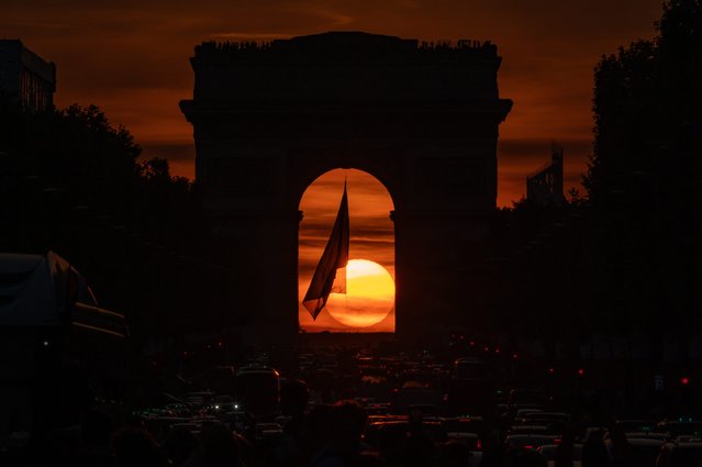 This photograph taken on May 9, 2024, shows the Arc de Triomphe monument on the Avenue des Champs Elysees at sunset in Paris. This event known as “Paris Henge” happens twice a year. (Photo by Stefano Rellandini/AFP Photo)