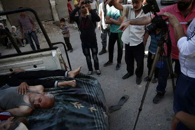 Syrian director Humam Husari (wearing pink) and cameraman Sami al-Shami (far right) operate a camera as they film a scene in the rebel-held besieged town of Zamalka, in the Damascus suburbs, Syria September 19, 2016. (Photo by Bassam Khabieh/Reuters)