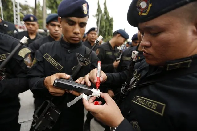 An officer of the Philippine National Police force tapes the muzzle of a gun at a police camp in Taguig City, south of Manila, Philippines, 22 December 2014. (Photo by Francis R. Malasig/EPA)
