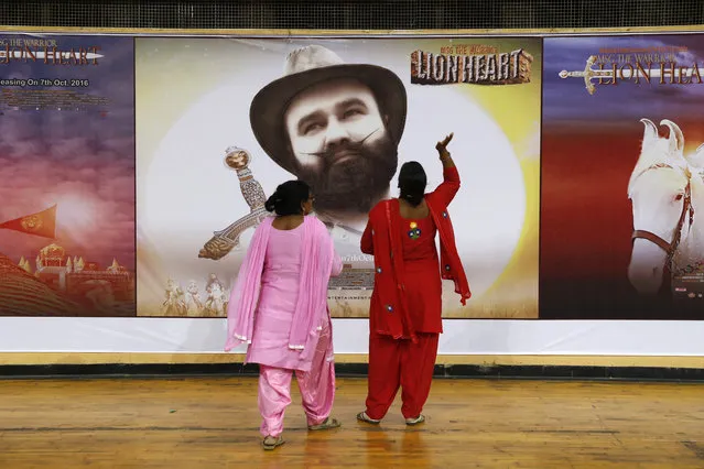 In this Wednesday, October 5, 2016 photo, devotees of Indian spiritual guru, who calls himself Saint Dr. Gurmeet Ram Rahim Singh Ji Insan, stands near a poster of his new film “MSG, The Warrior Lion Heart”, in New Delhi, India. The leader of the quasi-religious sect has launched a film franchise in which he stars as a Messenger of God, or MSG for short, with divine powers to save the world. He claims to have 50 million followers and runs a spiritual empire that promotes vegetarianism and campaigns against drug addiction. With a guaranteed audience among his followers, Insan said he's had little trouble getting his films released commercially in cinemas. (Photo by Tsering Topgyal/AP Photo)