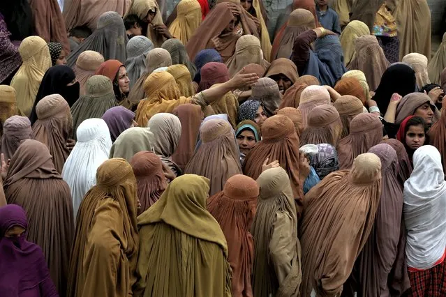 Women gather and wait their turn to get a free sack of wheat flour at a distribution point, in Peshawar, Pakistan, Wednesday, March 29, 2023. Pakistan's Prime Minister Shahbaz Sharif is providing free flour to deserving and poor families during the Muslim's holy month of Ramadan due to high inflation in the country. (Photo by Muhammad Sajjad/AP Photo)