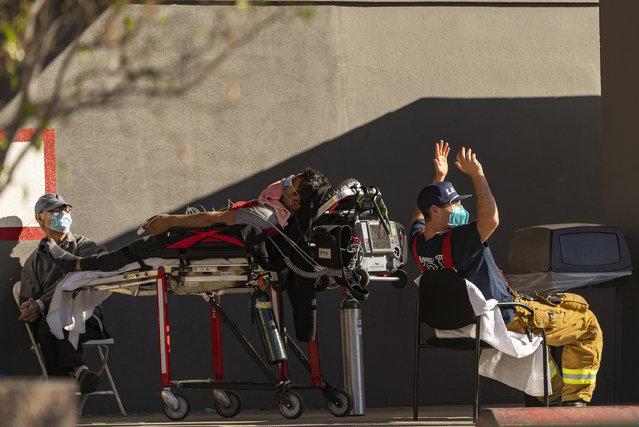 An unidentified patient receives oxygen on a stretcher, while Los Angeles Fire Department Paramedics monitor him outside the Emergency entrance, waiting for a room at the CHA Hollywood Presbyterian Medical Center in Los Angeles Friday, December 18, 2020. Increasingly desperate California hospitals are being “crushed” by soaring coronavirus infections, with one Los Angeles emergency doctor predicting that rationing of care is imminent. (Photo by Damian Dovarganes/AP Photo)