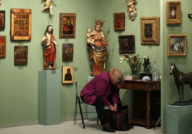 A woman sits in a gallery with church objects at the Cologne Fine Art 2015 fair in Cologne, Germany, November 17, 2015. Some 150 exhibitors are taking part in the Cologne Fine Art which offers a spectrum ranging from antiquities through to contemporary art from November 18 until 22, 2015. (Photo by Ina Fassbender/Reuters)