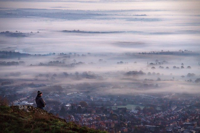 A walker observes the fog and mist at dawn from the Malvern Hills looking over Worcestershire, England on November 26, 2020. (Photo by Jacob King/PA Images via Getty Images)