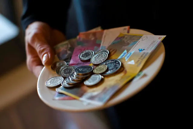 A waitress presents a plate with various Swiss Franc coins and notes in this picture illustration in a restaurant in Zurich, Switzerland, May 21, 2013. (Photo by Michael Buholzer/Reuters/Illustration)