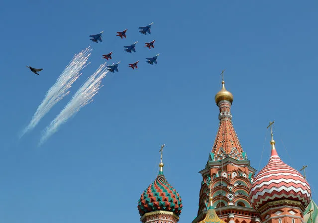 Russian army MiG-29 jet fighters of the Strizhi (Swifts) and Su-30 jet fighters of the Russkiye Vityazi (Russian Knights) aerobatic teams fly in formation during the rehearsal for the Victory Day parade, with St. Basil's Cathedral and a bird seen in the foreground, in central Moscow, Russia May 4, 2018. (Photo by Tatyana Makeyeva/Reuters)