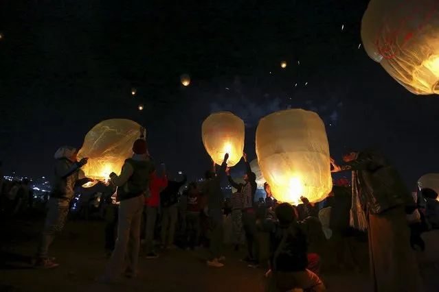 People light traditional home-made paper lanterns before releasing them into the sky, during the annual Tazaungdaing balloon festival in Taunggyi November 19, 2015. (Photo by Soe Zeya Tun/Reuters)